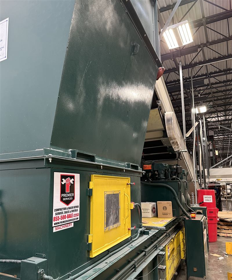Green industrial compactor with yellow access door