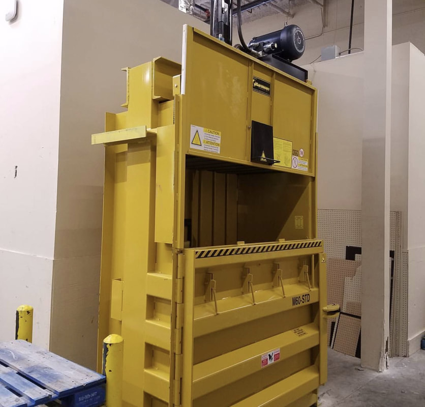 Yellow Harmony vertical baler installed indoors